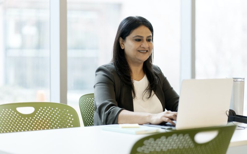 Confident positive Indian mature woman, a sales or executive manager typing text on laptop keyboard